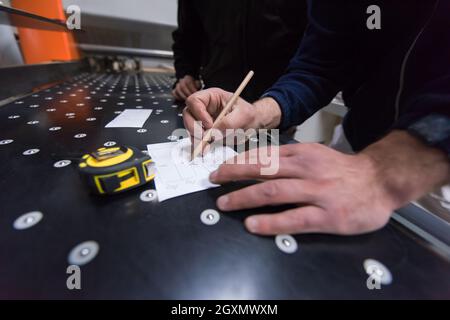 two young carpenters calculating and programming a cnc wood working machine in workshop. wood workers preparing a computer program for CNC machine at Stock Photo