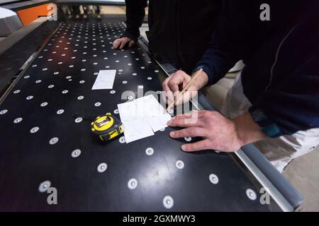 two young carpenters calculating and programming a cnc wood working machine in workshop. wood workers preparing a computer program for CNC machine at Stock Photo