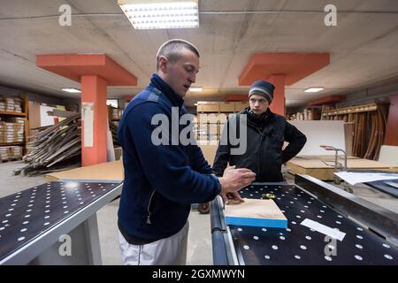 two young carpenters calculating and programming a cnc wood working machine in workshop. wood workers preparing a computer program for CNC machine at Stock Photo