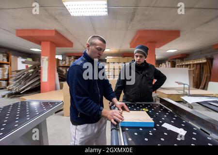 two young carpenters calculating and programming a cnc wood working machine in workshop. wood workers preparing a computer program for CNC machine at Stock Photo