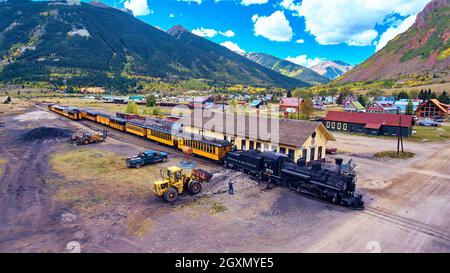 Train loading with coal in small mining town next to mountains Stock Photo
