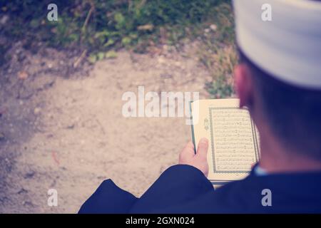 quran holy book reading by imam  on islamic funeral with white thumb stones graweyard background Stock Photo
