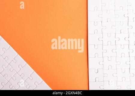 Top view flat lay of paper plain white jigsaw puzzle game texture on an orange background, quiz calculation concept Stock Photo