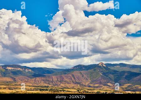 Large white clouds over landscape of desert mountains Stock Photo