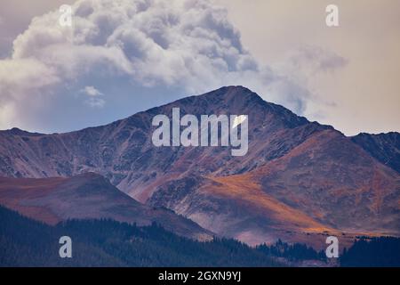 Red and dark gray mountain with large approaching clouds Stock Photo