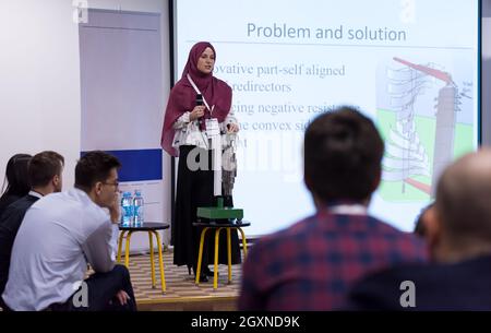 young muslim businesswoman with red scarf at business conference room giving public presentations. Audience at the conference hall. Entrepreneurship c Stock Photo