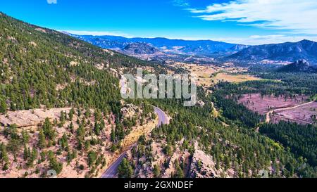 Road winding through large mountains with pine trees Stock Photo