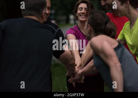 Group of healthy runners giving high five to each other while celebrating success after a training session. Stock Photo