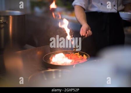 Chef cooking and doing flambe on food in restaurant kitchen Stock Photo