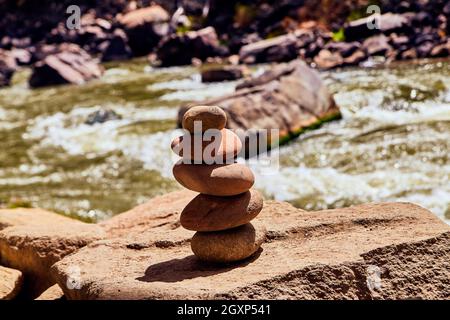 Cairn stack of smooth rocks with river in background Stock Photo