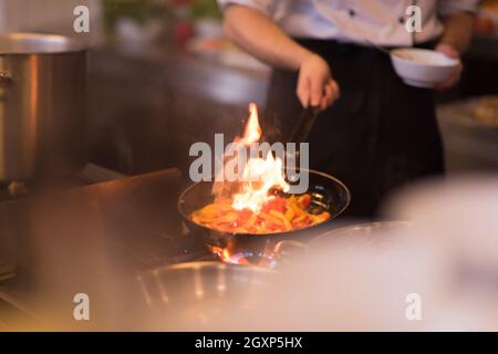 Chef cooking and doing flambe on food in restaurant kitchen Stock Photo