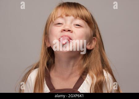 Portrait of an Adorable Red Haired Girl on a Grey Background. Stock Photo