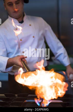 Chef cooking and doing flambe on food in restaurant kitchen Stock Photo