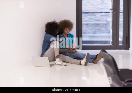 startup business and new mobile technology concept with young multiethnic couple in modern bright office interior working on laptop and tablet compute Stock Photo