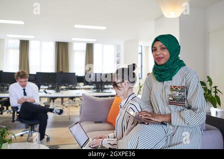 Multiethnic startup business team having brainstorming in relaxation area of modern office interior working on laptop and tablet computer Stock Photo
