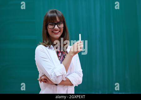 an attractive teacher with glasses explains to the students how to do the task on the board Stock Photo