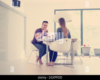 young beautiful handsome couple enjoying morning coffee and strawberries in their luxurious home villa Stock Photo