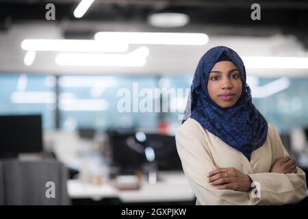 Portrait of young muslim african american female software developer with blue scarf standing at modern startup office Stock Photo