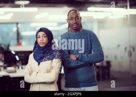 portrait of black muslim female software developer standing together with her african american male colleague at modern startup office Stock Photo