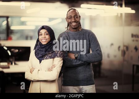portrait of black muslim female software developer standing together with her african american male colleague at modern startup office Stock Photo