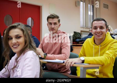 In the Classroom Multi Ethnic Students Listening to a Lecturer and Writing in Notebooks. Smart Young People Study at the College. Stock Photo