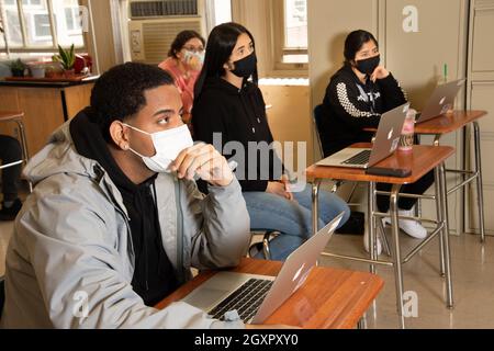 Education High School classroom scene, students listening, all wearing face masks to protect against Covid-19 infection Stock Photo