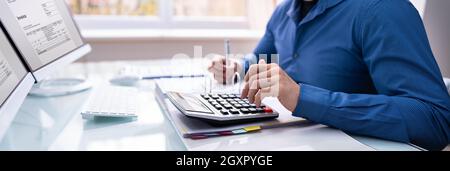 Bookkeeper Accountant Calculating Tax Invoice On Office Computer Stock Photo