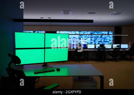 Empty interior of big modern security system control room with blank green screens, workstation with multiple displays, monitoring room with at securi Stock Photo