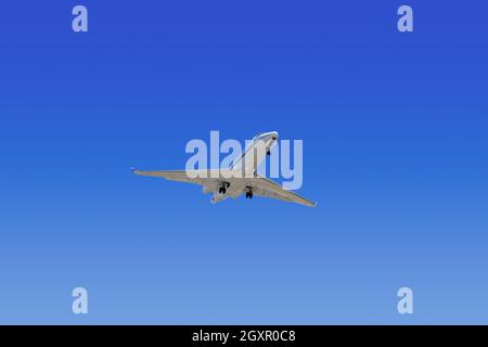 Private jet airplane coming in for a landing with clear blue sky Stock Photo