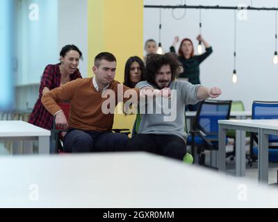 business people having fun while racing on office chairs in modern coworking open space office Stock Photo