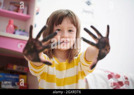 cute little girl at home painting with hands funny no tooth smile Stock Photo