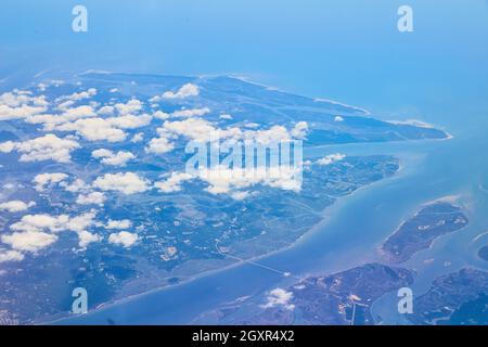 Airplane view of land with clouds covering Stock Photo