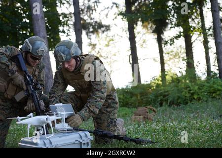 Modern Warfare Soldiers Squad are Using Drone for Scouting and Surveillance During Military Operation in the Forest. Stock Photo