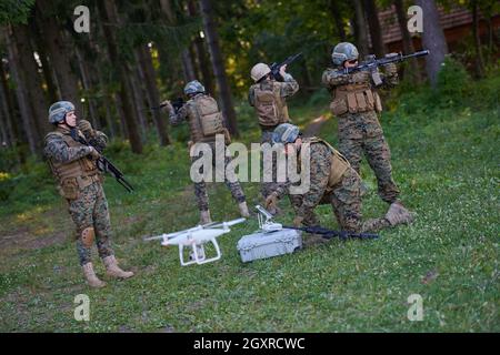 Modern Warfare Soldiers Squad are Using Drone for Scouting and Surveillance During Military Operation in the Forest. Stock Photo