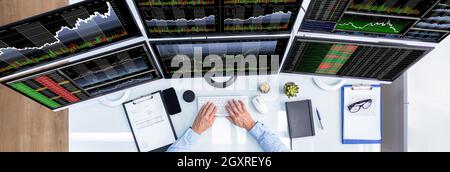Stock Exchange Analyst Using Multiple Computer Screens Stock Photo