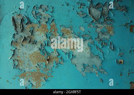 Teal paint peels to reveal a white wall with orange mold or rust spots in a grain elevator Stock Photo
