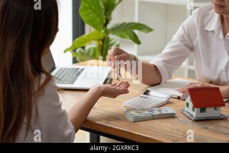 real estate agent holding house key to his client after signing contract agreement in office,concept for real estate, moving home or renting property. Stock Photo