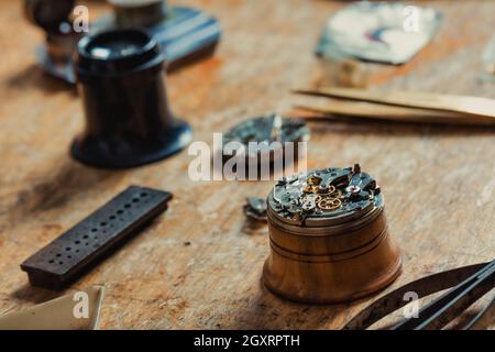 focus on Closeup detail of an old clock or watch mechanism, on a watchmakers workbench with hand tools Stock Photo