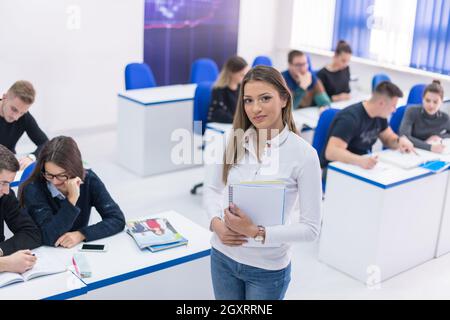 young beautiful female student with others writing notes in the classroom Stock Photo