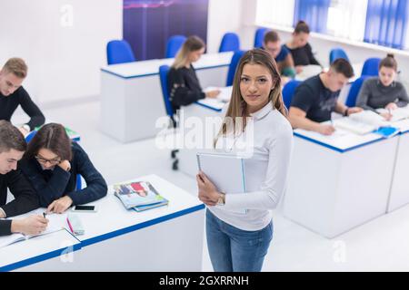 young beautiful female student with others writing notes in the classroom Stock Photo