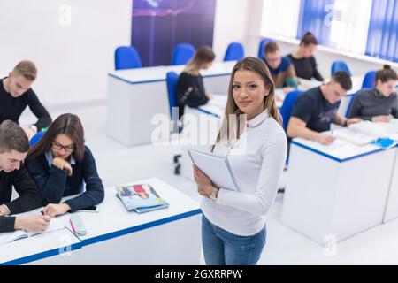 young beautiful female student with others writing notes in the classroom Stock Photo