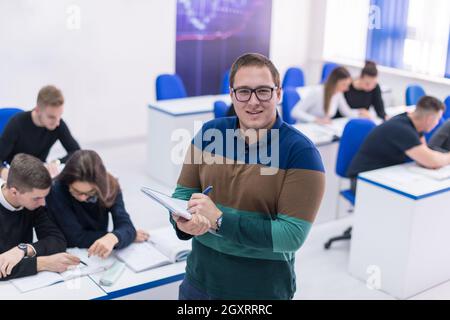 young male student with others writing notes in the classroom Stock Photo