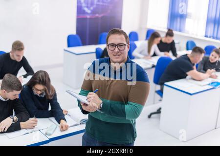 young male student with others writing notes in the classroom Stock Photo