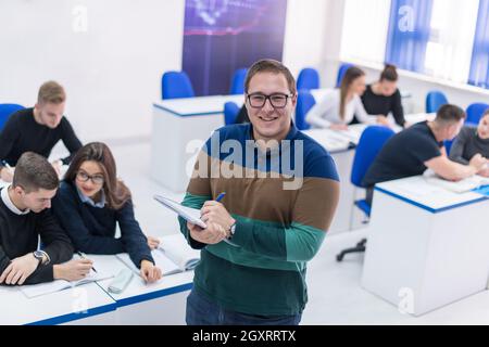 young male student with others writing notes in the classroom Stock Photo