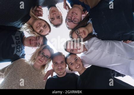 Group of young students in electronics classroom celebrating successfully finished project with holding their hands together, education and technology Stock Photo