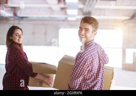 happy young casual business team carrying cardboard boxes with sunlight through the windows during moving in at new unfinished startup office building Stock Photo