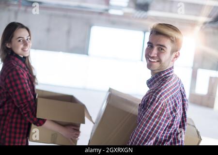 happy young casual business team carrying cardboard boxes with sunlight through the windows during moving in at new unfinished startup office building Stock Photo