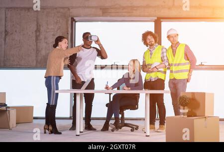 young multiethnic business team checking documents and business workflow on construction site using the virtual reality headset and laptop computer wi Stock Photo
