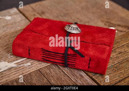 Detail of closed red leather journal with black thread on wood background Stock Photo