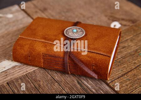 Small closed leather journal with concho and thread on wood boards Stock Photo
